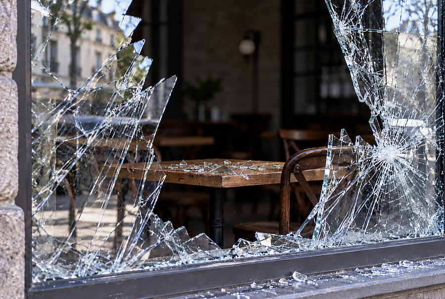 Vitrine brisée d’un café, avec des éclats de verre sur une table à l’intérieur